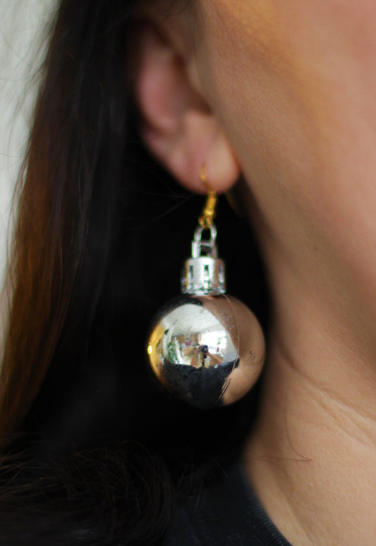 UK woman wearing sparkling green bauble earrings at a Christmas party.