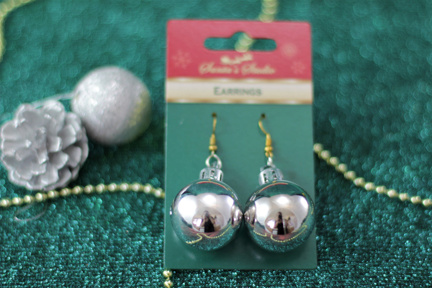 Close-up of 6cm silver bauble earring on gold-tone hook.