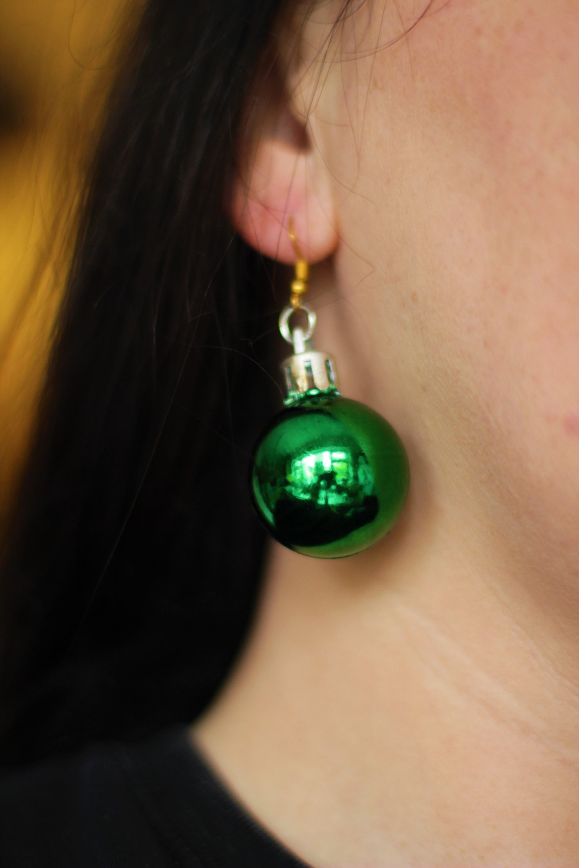 UK woman wearing sparkling green bauble earrings at a Christmas party.