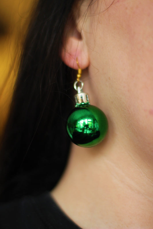 UK woman wearing sparkling green bauble earrings at a Christmas party.