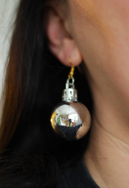 UK woman wearing sparkling green bauble earrings at a Christmas party.