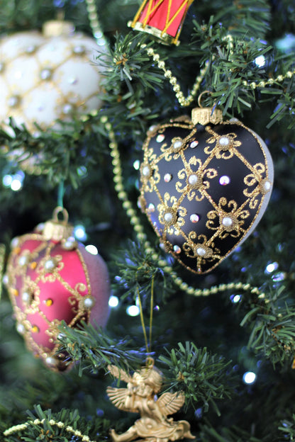 Elegant black heart Christmas bauble with Swarovski crystals displayed on a festive tree.