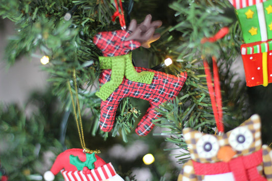 The 9 cm red plaid polyclay reindeer ornament hanging on a festive Christmas tree.