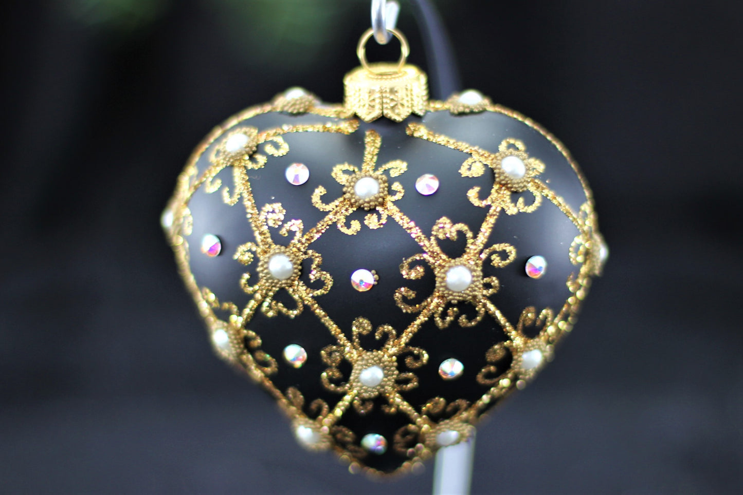 Close up of filigree pattern and genuine Swarovski crystal detail on black heart ornament.