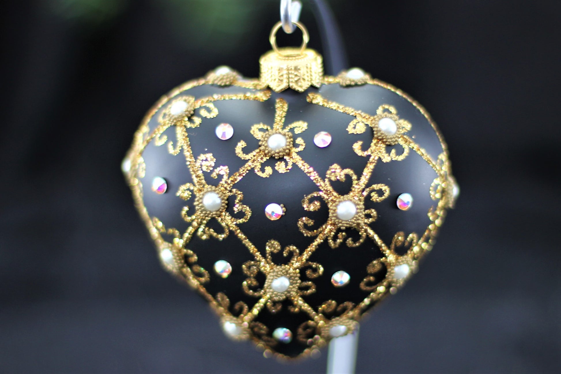 Close up of filigree pattern and genuine Swarovski crystal detail on black heart ornament.